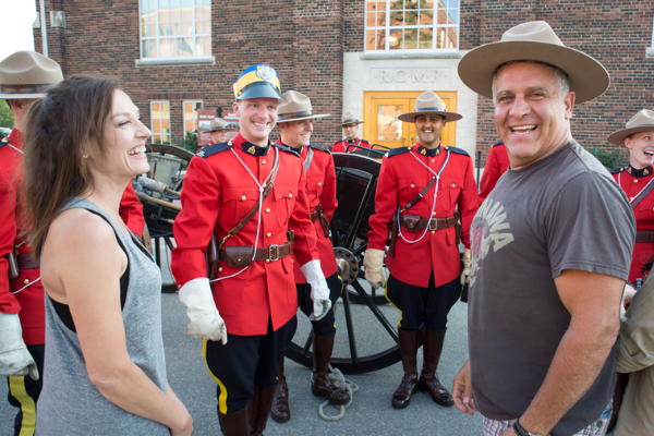 Participant at an RCMP event trying on an RCMP hat while members of the RCMP look on