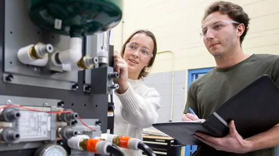 Two people handling a machine