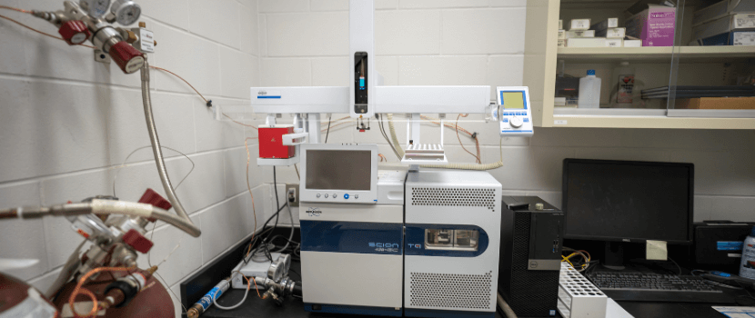 Person standing in front of triple quadrupole mass spectrometer and adding vile to the top
