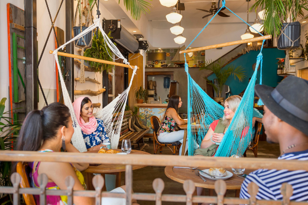 Four friends visiting, two sitting in hammocks and two at a table, at a local restaurant