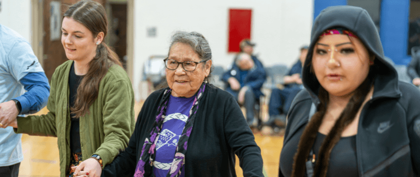 Four people holding hands participating in the round dance