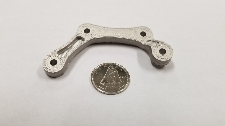Our first 3D printed metal part showing fine detail next to a dime