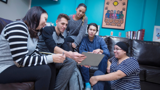 Five students sitting on a couch at the Indigenous Students' Centre looking at a laptop